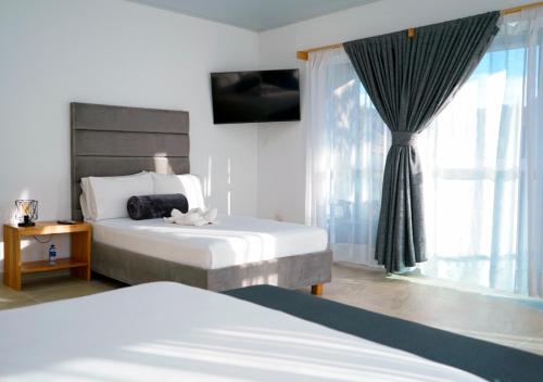 a hotel room with two beds and a window at Hotel Nova El Peñol in El Peñol