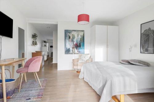 a white bedroom with a bed and a table and chairs at 5647-Gudhjem-Kirkevej-10-lejl-3 in Gudhjem