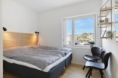 a bedroom with a bed and a chair and a window at 4797-Allinge-Havnevej-14-C-1-th in Allinge