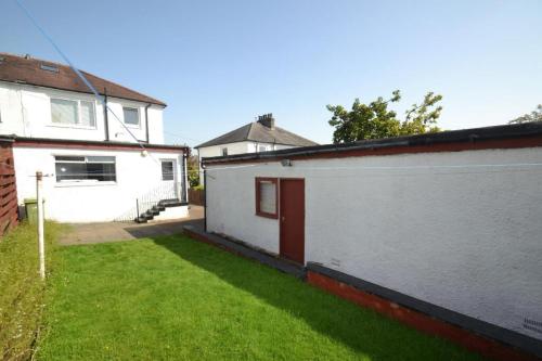 a backyard of a house with a grass yard at Spacious 4-Bedroom Family Home in Giffnock Glasgow in Pollokshaws