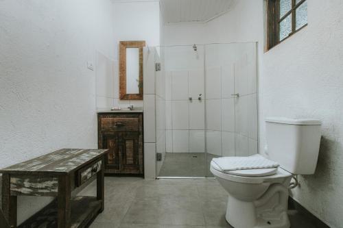a bathroom with a toilet and a glass shower at Pousada Hakuna Matata in Morretes