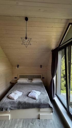 a bed in a wooden room with a large window at Перлина Гір in Yablunytsya