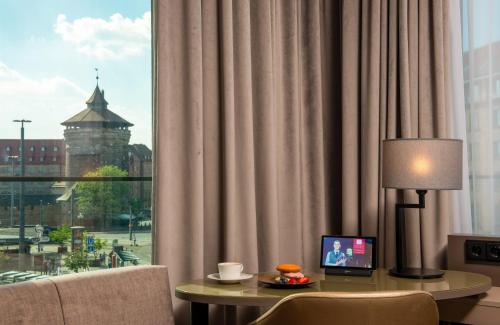 a hotel room with a table with a laptop on it at Leonardo Royal Hotel Nürnberg in Nuremberg