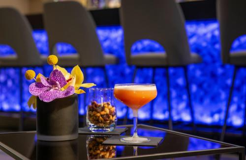 a drink and a vase with flowers on a table at Leonardo Royal Hotel Nürnberg in Nuremberg