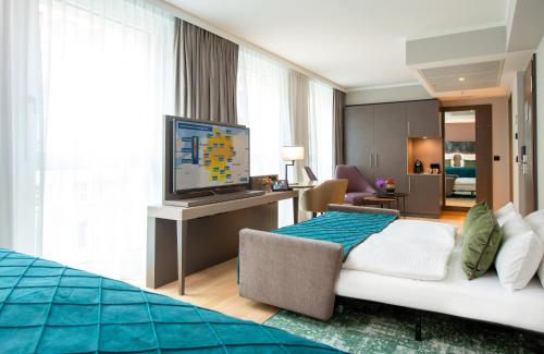 a hotel room with a bed and a flat screen tv at Leonardo Royal Hotel Nürnberg in Nuremberg