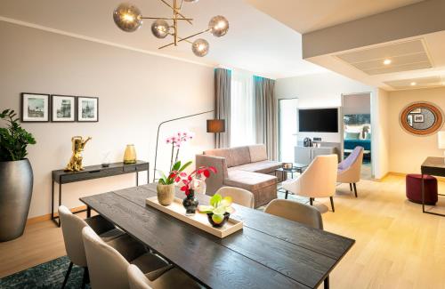 a living room with a dining table and a living room at Leonardo Royal Hotel Nürnberg in Nuremberg