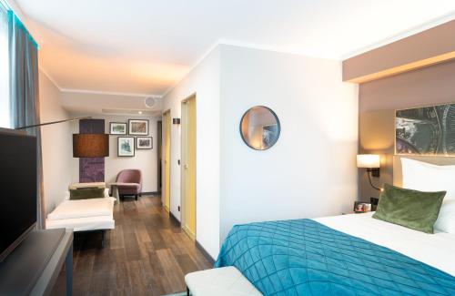 a hotel room with a bed and a desk at Leonardo Royal Hotel Nürnberg in Nuremberg