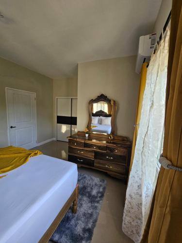 a bedroom with a bed and a mirror and a dresser at Tranquility Loft in Ocho Rios