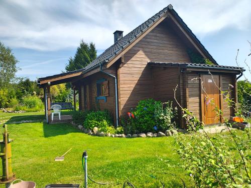 ein kleines Haus mit einem grünen Hof davor in der Unterkunft Przystań Natury - Drewniany Dom Wakacyjny in Domysłów
