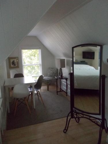 a bedroom with a bed and a mirror and a table at Seaway Manor B&B in Gananoque