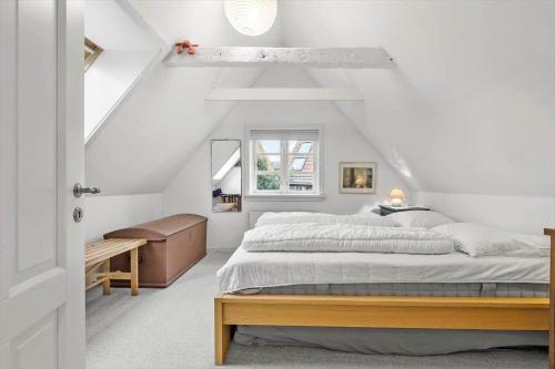 a white bedroom with a bed and a desk at 5561-Gudhjem-Kirkevej-8 in Gudhjem