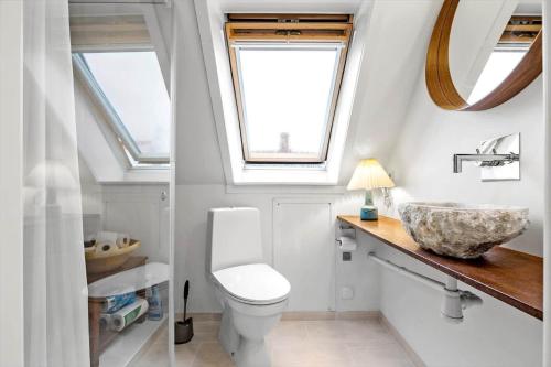 a bathroom with a toilet and a sink and a window at 5561-Gudhjem-Kirkevej-8 in Gudhjem