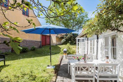 a table with a blue umbrella in a yard at 5561-Gudhjem-Kirkevej-8 in Gudhjem