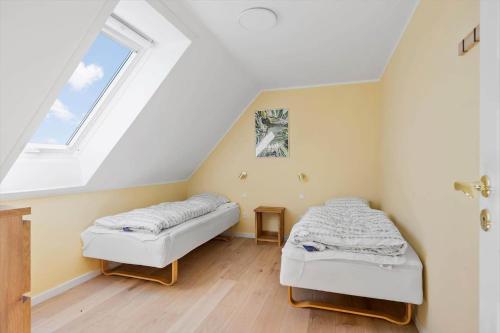 a attic room with two beds and a window at 3691-Nexo-Stensebyvejen-32 in Neksø