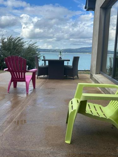 two chairs and a table with a view of the water at Cois Cuan in Ballynagaul