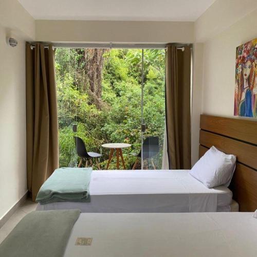 a bedroom with two beds and a window with a table at Hotel Serra do Gandarela in Rio Acima