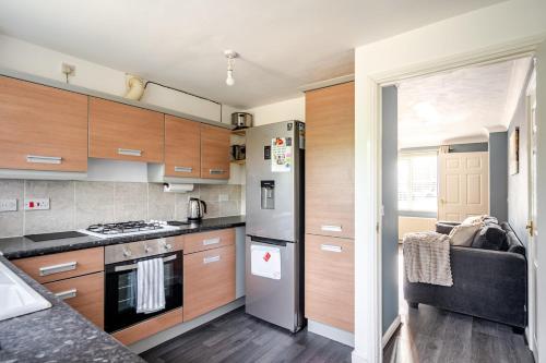 eine Küche mit Holzschränken und einem Edelstahlkühlschrank in der Unterkunft Cozy 2-Bed Home in Middleton in Middleton