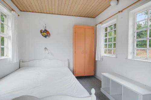a white bedroom with a bed and two windows at 3671-Nexo-Dunhammervej-3 in Neksø