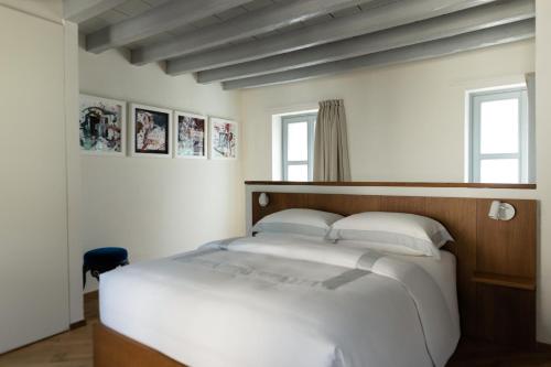 a bedroom with a white bed and two windows at Dé Corner Rooms and Suites in Soncino