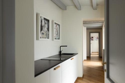 a kitchen with white cabinets and a black counter top at Dé Corner Rooms and Suites in Soncino
