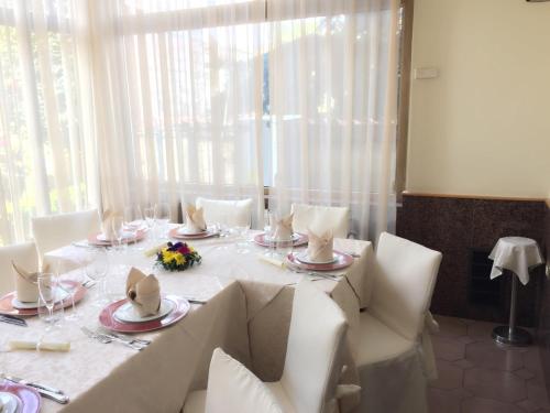 un tavolo bianco con sedie bianche e una tovaglia bianca di Hotel Giardino degli Aranci a Frattamaggiore