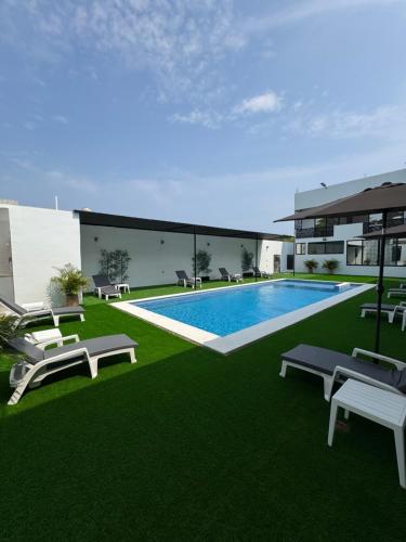 a building with a swimming pool and green grass at Houzze Plety in Brisas de Zicatela
