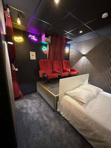 a room with a bed and two red chairs at Cocon Jacuzzi et cinéma 4K B in Bordeaux