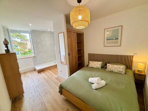 ein Schlafzimmer mit einem grünen Bett mit zwei Handtüchern darauf in der Unterkunft La Pinède, Proche gare, Centre ville, Netflix in Bourgoin