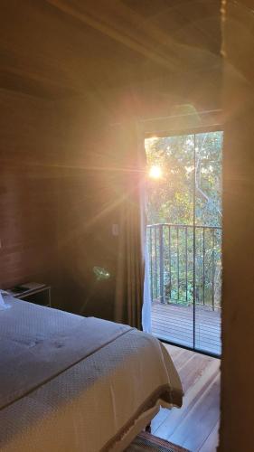 a bedroom with a bed and a window with the sunlight at Suítes La Reserve in Campos do Jordão