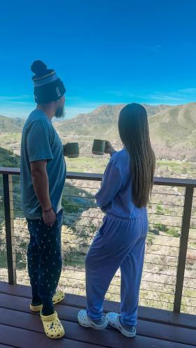 a man and a woman standing next to a fence at 4 Kings Log Cabin 150 Acres Spectacular Views in Three Rivers