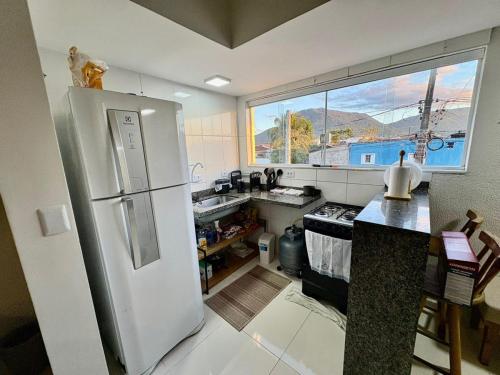 a kitchen with a white refrigerator and a large window at Casa Para Hóspedes em Peruíbe - SP in Peruíbe