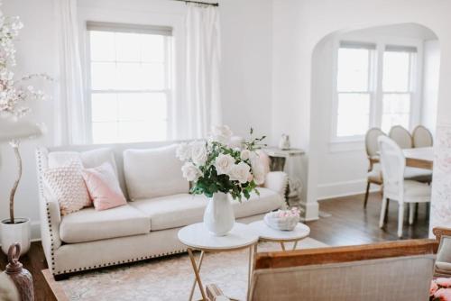 a living room with a couch and a table with flowers at The Pink House in Downtown Clarksville in Clarksville
