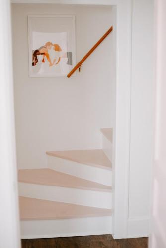 a staircase in a white room with a picture on the wall at The Pink House in Downtown Clarksville in Clarksville