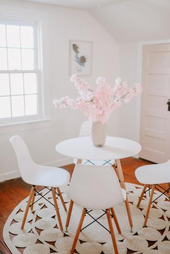 a white table with white chairs and a vase of flowers at The Pink House in Downtown Clarksville in Clarksville