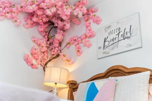 a branch of pink flowers on a wall next to a bed at The Pink House in Downtown Clarksville in Clarksville