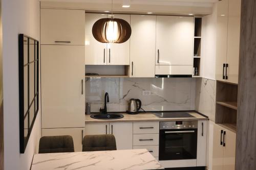 a kitchen with white cabinets and a table with chairs at Stan na dan Sneguljica in Sarajevo