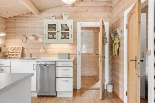 a kitchen with wooden walls and white cabinets and a door at 1444-Aakirkeby-Poseregardsvejen-15 in Vester Sømarken
