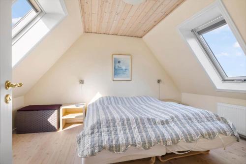 a attic bedroom with a bed and two windows at 5613-Allinge-Bohnebakken-21-Lejl-1 in Allinge