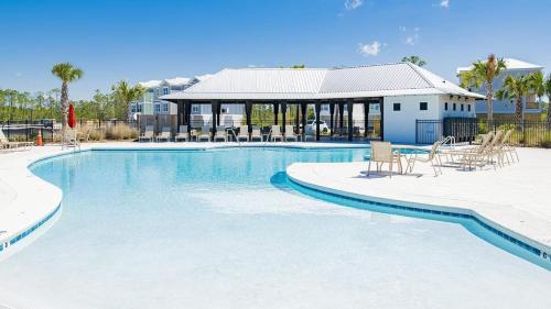 a large swimming pool with chairs and a building at Coastal Bummz in Orange Beach