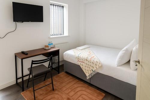 a bedroom with a bed and a desk with a television at City Centre Room - Walk to Station - Fast Wi-Fi in Coventry