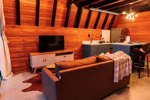 a living room with a brown couch and a kitchen at Chalé com hidro e vista! in Imaruí