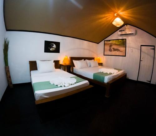two beds in a room with two lamps on them at Safaria Lodge Wilpattu in Pahala Maragahawewa