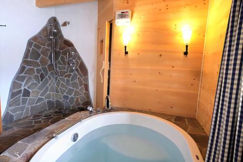 a bath tub in a bathroom with a stone wall at Chratidudel - Ski-in , Ski-out in Bettmeralp