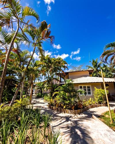 a house with palm trees in front of it at Hotel Espelho D'Água Arraial e Beach Club in Arraial d'Ajuda