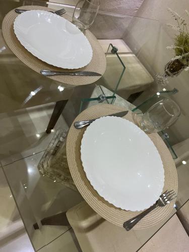 two plates on a glass table with hats and utensils at Apartamento suíte com estacionamento in Porto Alegre