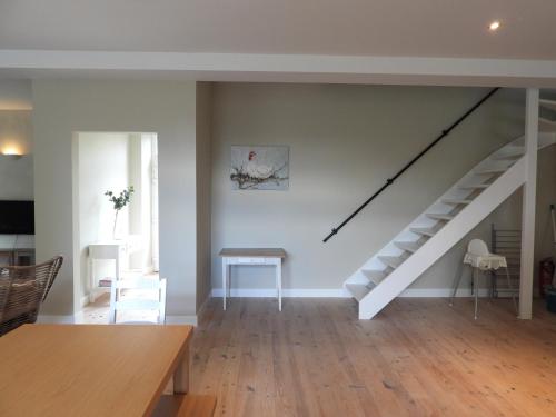 a living room with a staircase and a table at Ô lit de l'Ourthe in Hotton