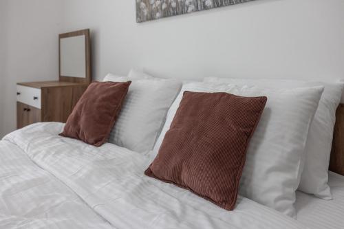 a white bed with two brown pillows on it at 19th Floor Pool,Spa,Fitness Sky View Free Parking in Skopje