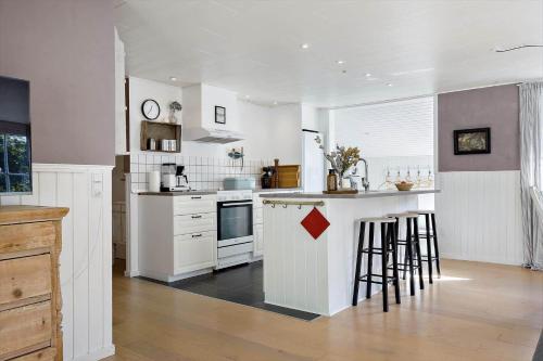 a kitchen with white cabinets and an island with bar stools at LF391-Vestervig-Gunhildsvej-1 in Vestervig