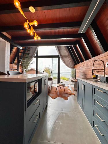 a kitchen with blue cabinets and a wooden ceiling at Chalé com hidro e vista! in Imaruí