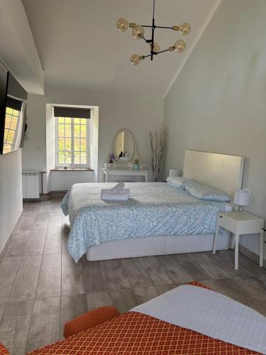 a white bedroom with a bed and a mirror at Casa con piscina in Cedeira